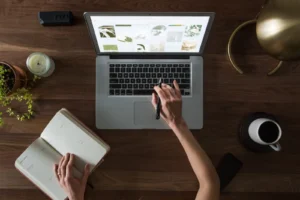 Vogelperspektive auf einen Schreibtisch mit Notebook, Notizbuch und Kaffeetasse